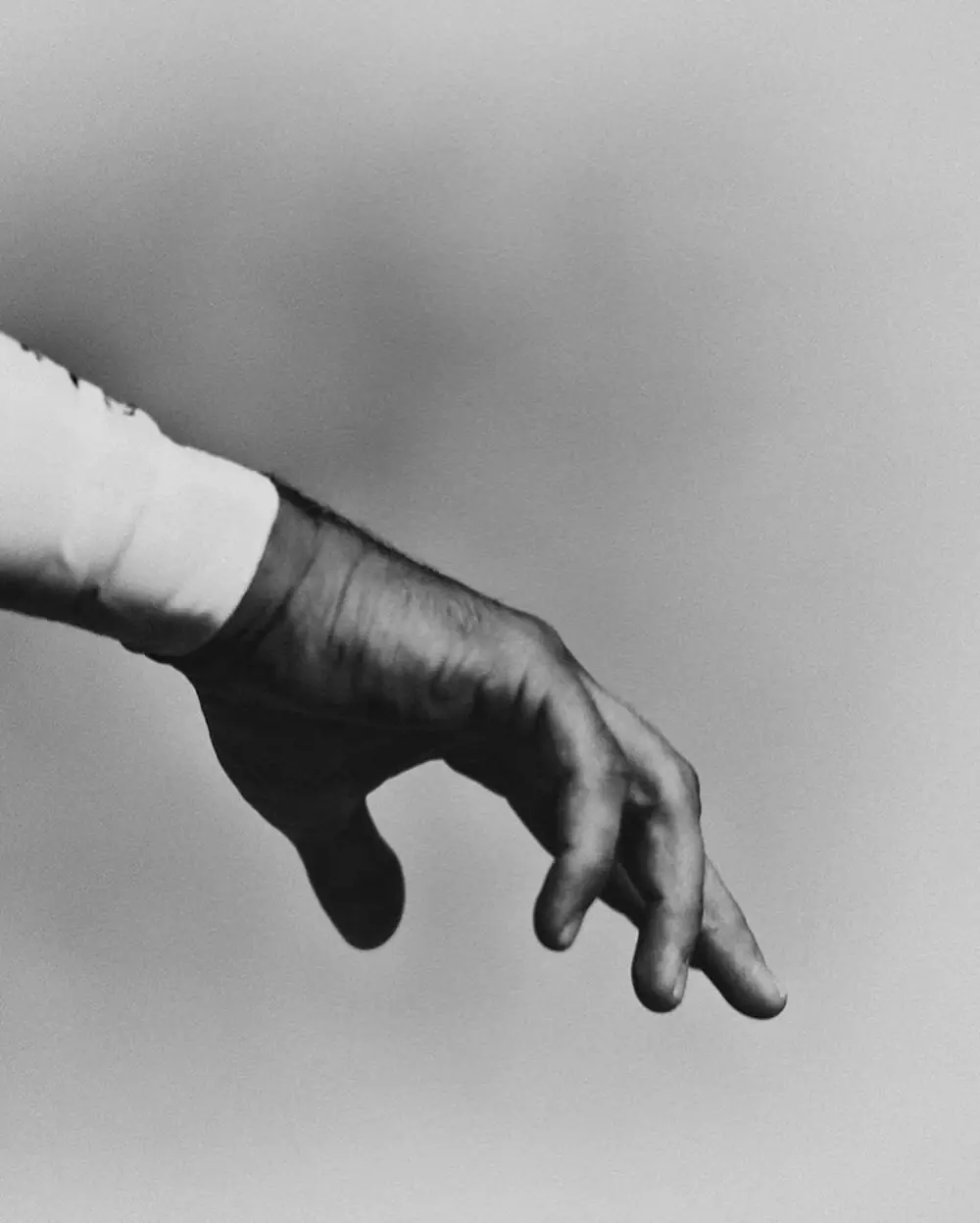 A hand at rest against a grey sky